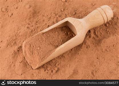 cocoa powder in wooden scoop closeup background