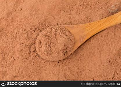 cocoa powder in wooden spoon closeup background