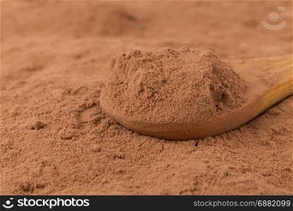 cocoa powder in wooden spoon closeup background