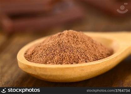 Cocoa powder on wooden spoon with chocolate pieces in the back (Very Shallow Depth of Field, Focus one third into the cocoa)