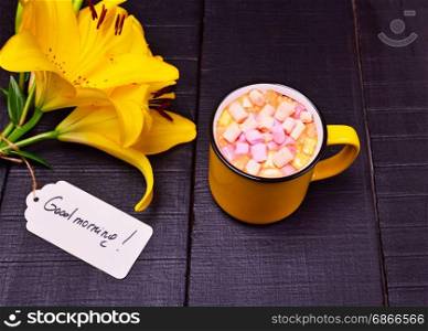 Cocoa with marshmallows in a yellow mug, black wooden background