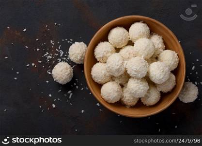 Coconut candies bowl on dark table background flat lay top view