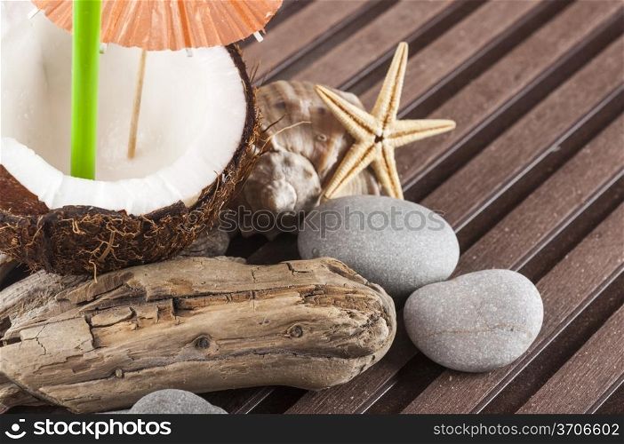 coconut cocktail with green drinking straw and cocktail umbrella pebbles, seastar, seashell