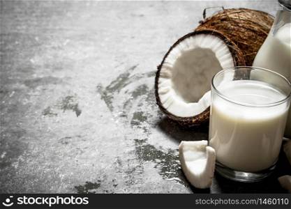 Coconut milk in a jar with pieces of coconut. On a stone background.. Coconut milk in a jar