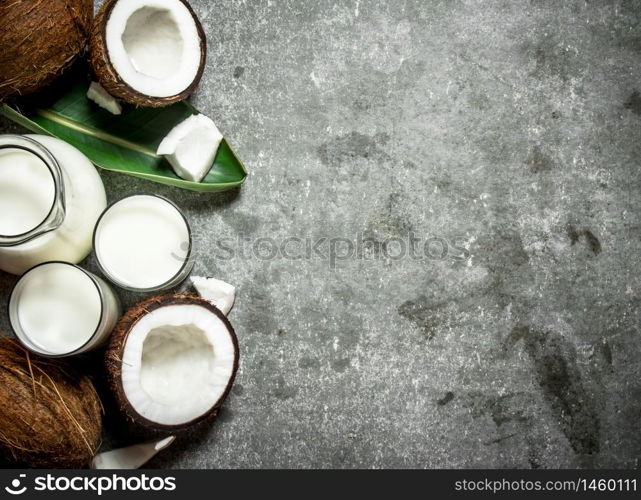 Coconut milk in a jar with pieces of coconut. On a stone background.. Coconut milk in a jar