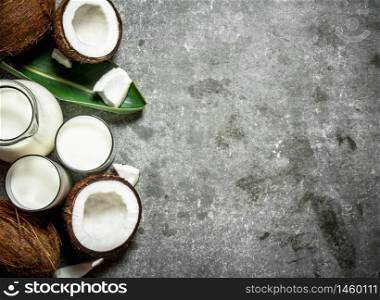 Coconut milk in a jar with pieces of coconut. On a stone background.. Coconut milk in a jar