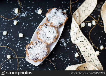 coconut muffins on a black background with candied coconut and lace ribbon. coconut muffins on a black background