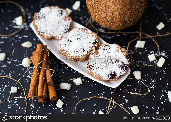 coconut muffins on a black background with cinnamon sticks and whole coconut. coconut muffins on a black background