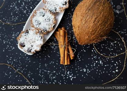 coconut muffins with chocolate and cinnamon on a black background and whole coconut. coconut muffins on a black background