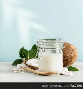 Coconut oil in jar with fresh coconut and tropical leaf shadow, Spa cosmetic and food ingredient, square composition
