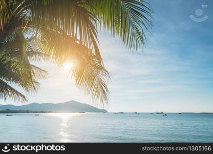 Coconut plam tree with sun and blue sky at tropical beach, Summer vacation concept