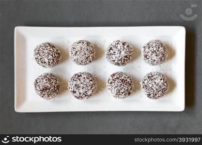 Coconut rum balls on plate, photographed overhead on slate with natural light (Selective Focus, Focus on the top of the balls)