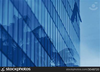 Coconut trees reflection in office building glass wall. Double exposure. Color of the year 2020 classic blue toned