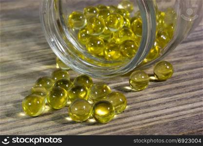 Cod fish oil gel capsules in glass jar on wooden background
