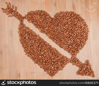 Coffe beans in the shape of a big heart, isolated on wood