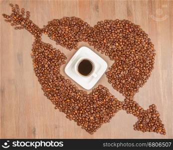 Coffe beans in the shape of a big heart, isolated on wood