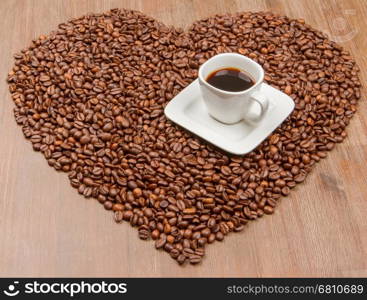 Coffe beans in the shape of a big heart, isolated on wood