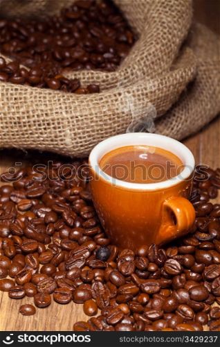 Coffe cup surrounded by toasted beans