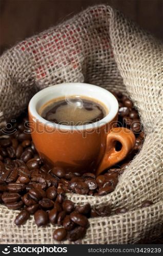Coffe cup surrounded by toasted beans