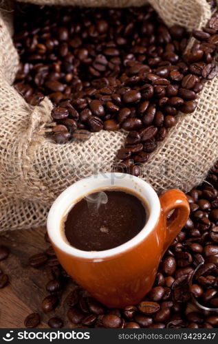 Coffe cup surrounded by toasted beans