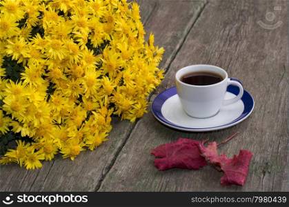 coffee, a bouquet of yellow flowers and nearby a red leaf, on a wooden table, fall, a still life a subject drinks