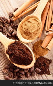 Coffee beans and cinnamon milled closeup in wooden spoons