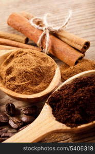 Coffee beans and cinnamon milled closeup in wooden spoons