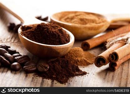 Coffee beans and cinnamon milled closeup in wooden spoons