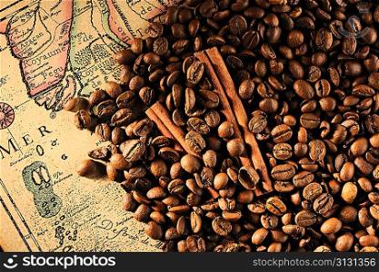 Coffee beans and cinnamon still life over old map