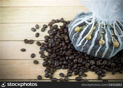 Coffee beans and decorated white sack on wood background&#xA;