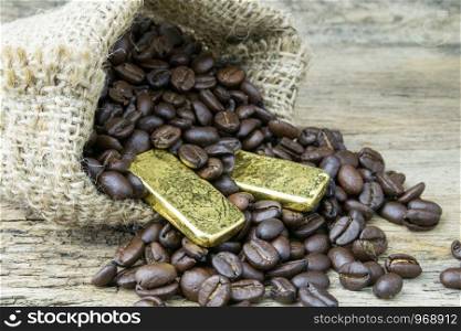 Coffee beans and Gold Bullion in sackcloth bag on wooden background