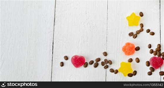 Coffee beans and jelly candies on a white background. There is a place for your text.