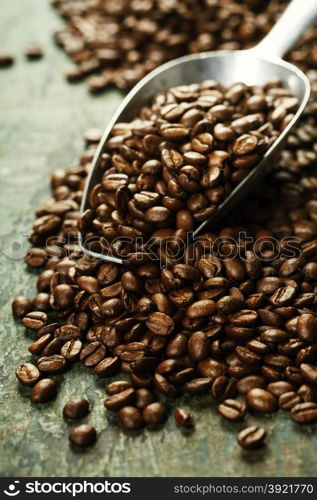 Coffee beans and metal scoop on wooden background