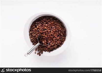 Coffee beans and scoop on white background texture. Roasted coffee bean on table