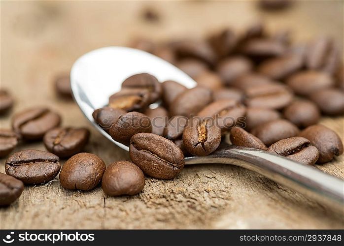 Coffee beans and spoon macro on wooden background