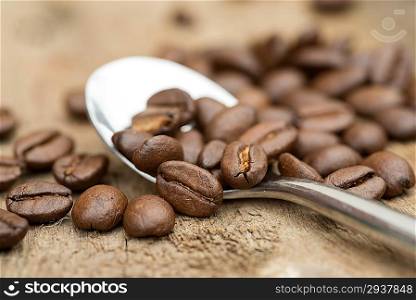 Coffee beans and spoon macro on wooden background
