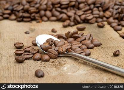 Coffee beans and spoon on wooden background