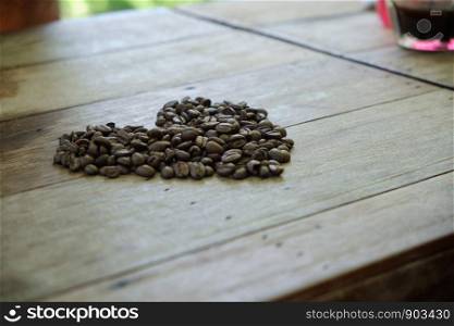 Coffee beans are placed on a wooden table. Heart shape