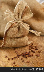 Coffee beans around a hessian bag on wooden board