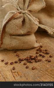Coffee beans around a hessian bag on wooden board