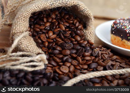 Coffee beans around a hessian bag on wooden board