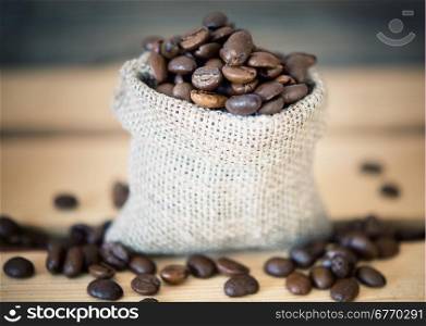 coffee beans in a burlap sack on wooden background