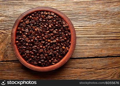 Coffee beans in a clay dish with nice texture on aged wood table background