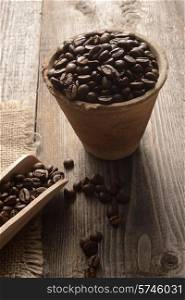 coffee beans in a clay pot on wooden background