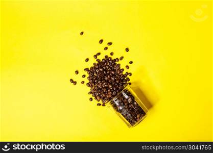 Coffee beans in a glass jar on yellow background, flat lay. Coffee beans on yellow background. Coffee beans on yellow background