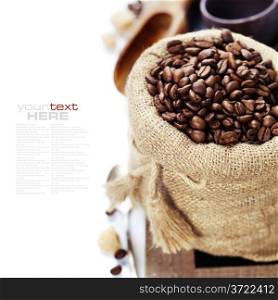 Coffee beans in burlap sack with wooden scoop over white (with sample text)