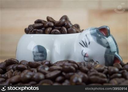 Coffee beans in cat ceramic pot on wood background&#xA;