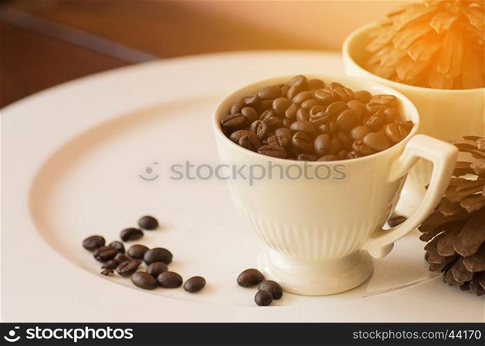 Coffee beans in cup on white plate with warm light effect , vintage stlye,selective focus.