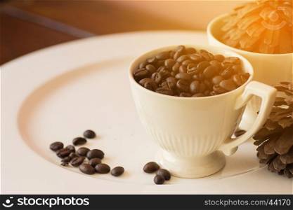 Coffee beans in cup on white plate with warm light effect , vintage stlye,selective focus.