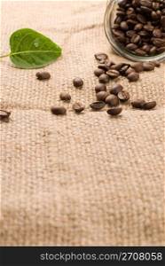 Coffee beans in glass jar on brown burlap background
